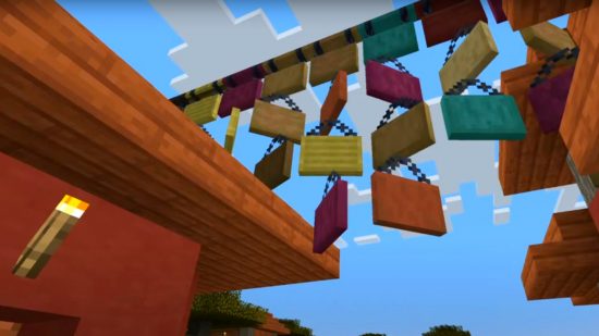 Señales colgantes de Minecraft utilizadas como banderines sobre un pueblo.